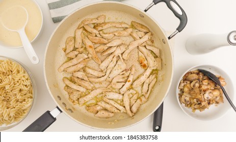 Chopped Chicken Meat Close Up On Frying Pan Directly From Above. Pasta With Chicken, Mushrooms, And Alfredo Sauce Recipe