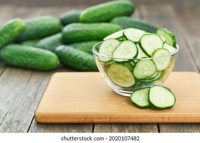 chopped fresh cucumber slices in a clear glass bowl on a wooden table, rustic style. Fresh cucumber. lot of cucumbers in a wooden bowl.