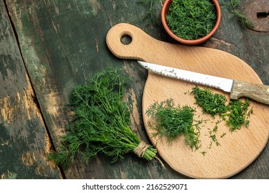 Chopped fresh dill on a cutting Board and a bunch of dill preparation for freezing serving size organic healthy ething natural product portion on a wooden table. Top view,