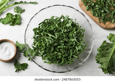 Chopped fresh green curly kale in a transparent salad bowl for making a healthy salad on a light gray background, top view, close up.  - Powered by Shutterstock