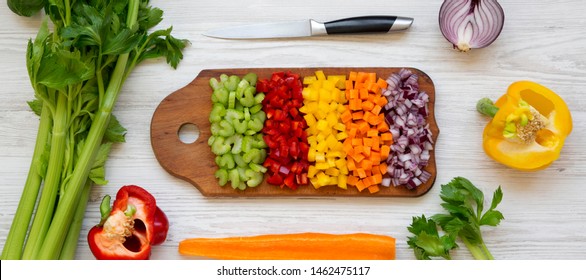 Chopped Fresh Vegetables (carrot, Celery, Red Onion, Peppers) Arranged On A Cutting Board On A White Wooden Background, Top View. From Above, Overhead, Flat Lay.