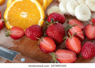 Chopped fruit (strawberries, oranges, banana) on wooden cutting board. Close-up. Healthy food, fresh salad preparation, clean-eating concept. - Powered by Shutterstock