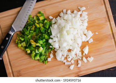 Chopped Green Bell Pepper And Onion On A Bamboo Cutting Board: Overhead View Of Diced Vegetables On A Wooden Chopping Board