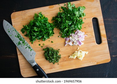 Chopped Herbs on a Bamboo Cutting Board: Chopped parsley, cilantro, oregano, shallots, and garlic on a bamboo cutting board - Shutterstock ID 1969657906