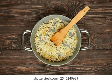 Chopped onions and garlic are sauteed in a pan with a wooden spatula, creating a flavorful base for a meal on a rustic wooden table. The scene captures the essence of home cooking. - Powered by Shutterstock