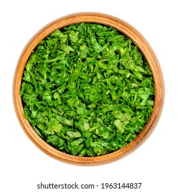 Chopped parsley, in a wooden bowl. Fresh, flat leaved parsley, green leaves of Petroselinum crispum, used as herb, spice and vegetable. Close-up, from above, isolated over white, macro food photo. - Powered by Shutterstock