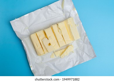 Chopped pieces of butter milk butter on a blue background. - Shutterstock ID 1949971882