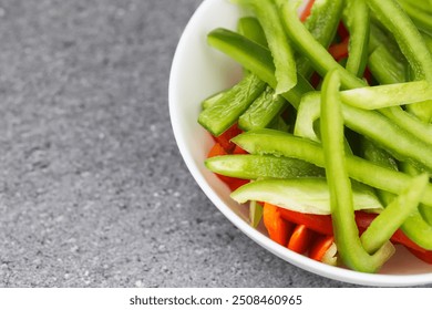 Chopped red and green bell peppers in white ceramic bowl.Vibrant colors dinner salad textures. Empty copy space kitchen counter background. - Powered by Shutterstock