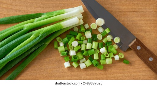 chopped scallions or spring onion on a wooden cutting board, top view. Spring onion and a knife. - Powered by Shutterstock