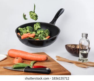 Chopped Sliced Diced Carrot Broccoli White Button Mushroom Red Chili Flying Dropping Gravity Defying On Floating Elevated Metal Frying Pan Cooking Board Bowl Oil Knife On White Background