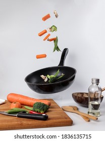 Chopped Sliced Diced Carrot Broccoli White Button Mushroom Red Chili Flying Dropping Gravity Defying On Floating Elevated Metal Frying Pan Cooking Board Bowl Oil Knife On White Background