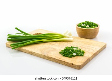 Chopped spring onions on wooden cutting board.