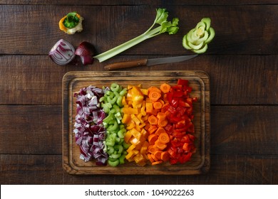 Chopped vegetables arranged on cutting board on wooden table, top view
