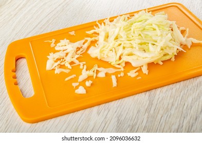 Chopped White Cabbage On Orange Cutting Board On Wooden Table