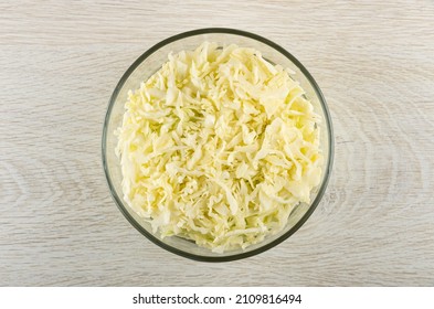 Chopped White Cabbage In Transparent Glass Bowl On Wooden Table. Top View