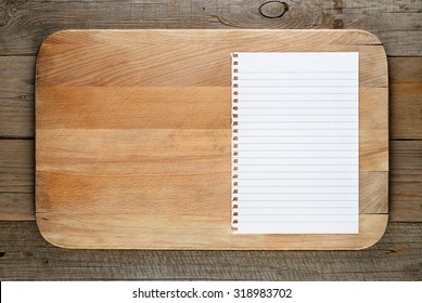 Chopping Board And Paper For Recipe On Wooden Background