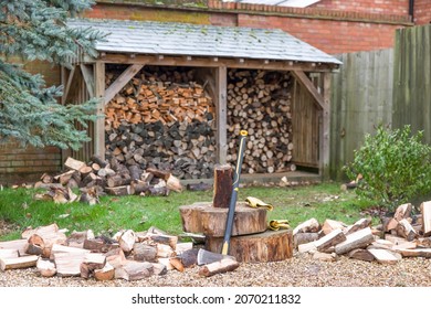 Chopping firewood. Axe and log pile outside a log store in a UK garden