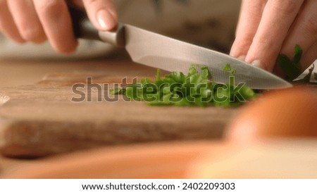 Chopping Fresh Parsley on Wooden Board, Cooking Action. Close-up, shallow dof.