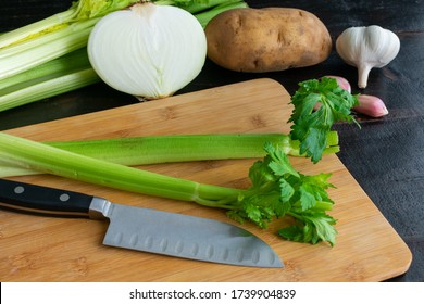 Chopping Fresh Vegetables: Celery, onion, potato, and garlic on a bamboo cutting board