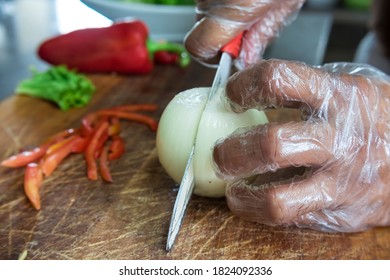 Chopping An Onion While Wearing Clear Plastic Gloves. Hygiene Or Quarantine Procedure In A Restaurant.