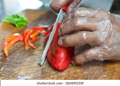 Chopping An Red Bell Pepper While Wearing Clear Plastic Gloves. Hygiene Or Quarantine Procedure In A Restaurant.