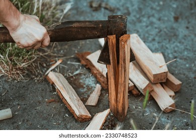 Chopping wood for the fire with an axe. A man's hand with an axe chopping wood, close-up. Preparing for the barbecue. Making firewood. Lumberjack - Powered by Shutterstock