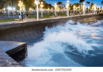 Choppy seas alongside Rizal pedestrian promenade stretch,after sunset,lit by street lamps,during an evening breeze.Popular area for people to gather in the evening,and stroll the sea wall.