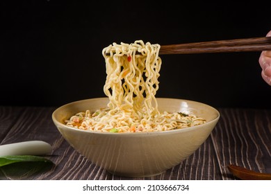 chopsticks with cooked instant noodles on wooden background - Shutterstock ID 2103666734
