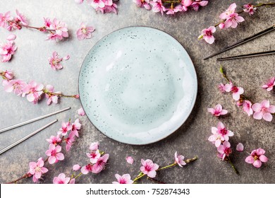 Chopsticks And Sakura Branches On Gray Stone Background. Japanese Food Concept. Top View, Copy Space