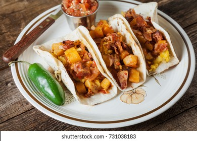 Chorizo Sausage, Eggs, Bacon And Potato Hash Breakfast Tacos On Rustic Wooden Surface