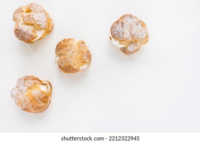Choux Bun with whipped cream and sugar powder on top on white background. Delicate choux pastry dessert. French cream puff. Top view, copy space - Shutterstock ID 2212322945