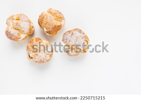 Choux Bun with whipped cream and sugar powder on top on white background. Delicate choux pastry dessert. French cream puff. Top view, copy space