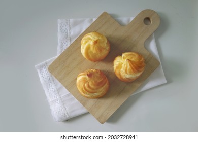 Choux Cream Cake Traditional French Dessert Displayed On Wooden Board. Tasty Creampuff Choux Isolated On White Background                