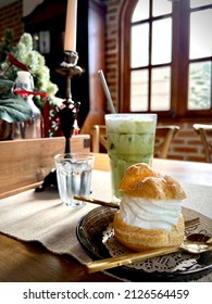 Choux Cream with Milk Green Tea Placed on the dining table in a cafe with natural light coming from the windows in the background