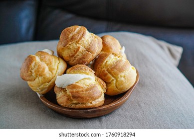 Choux Cream Puff Custard Whipped Cream Filling on a wooden plate and being put on the pillow - Shutterstock ID 1760918294