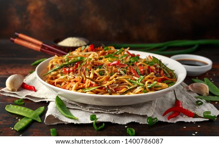 Chow mein, noodles and vegetables dish with wooden chopsticks