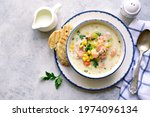 Chowder - thick potato soup with trout ( salmon ) and cream in a white bowl on a light slate, stone or concrete background. Top view with copy space.