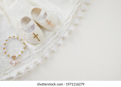 Christening Background With Baptism Baby Dress, Shoes, And Cross On Pastel Background