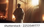 Christian Bishop Standing in Front of a Window In Church, Reflecting on Earthly Life and Mortality. He is Illuminated by the Light of Faith and Trust in the Guidance From Jesus Christ and the Bible