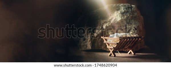 Christian Christmas concept. Birth of Jesus Christ.\
Wooden manger in cave background. Copy space. Nativity scene\
symbol. Jesus is reason for season. Salvation, Messiah, Emmanuel,\
God with us, 