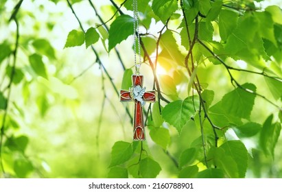 Christian cross with image of a dove on birch branches, sunny blurred green natural background. symbol of Holy Spirit. Holy Trinity Sunday, festive Pentecost day. Faith in God, Church holiday concept