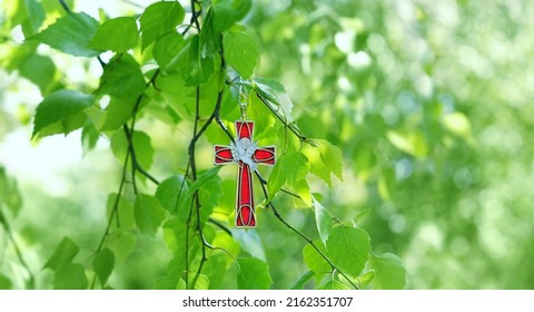 Christian cross with image of a dove on birch branches, blurred green natural background. symbol of Holy Spirit. Holy Trinity Sunday, festive Pentecost day. Faith in God, Church holiday concept