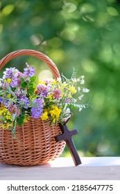 Christian cross and meadow flowers in wicker basket on table, natural background. Herbal consecration - traditional customs of August 15, day of the Assumption of Mary, know as Divine Mother of Herbs - Shutterstock ID 2185647775