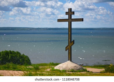 Christian cross on a green hill against clouds