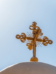 Christian Cross On A Mound Against A Blue Sky With White Clouds. Christian Symbol. Religion And Culture. Catholicism And Protestantism. Place Of Crucifixion. Easter. Cross Against Blue Sky