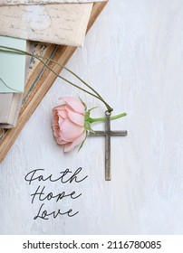 Christian cross, rose flower, old books on white abstract table background. "Faith. hope. love" - religion quote. cross, symbol of Easter, Lent, Christianity religion. flat lay	