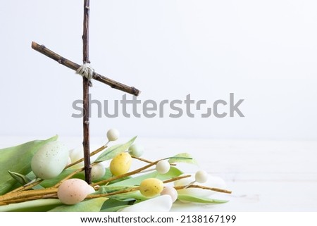 Christian cross with white tulips and easter eggs