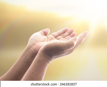 Christian devotion concept: Prayer open empty hands to praying for forgiveness from God over spiritual light background.