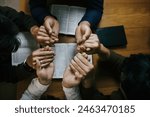 Christian Family prayer and worship. Christian group of people holding hands and praying worships to believe and Bible on a wooden table prayer meeting concept. Church Community pray together