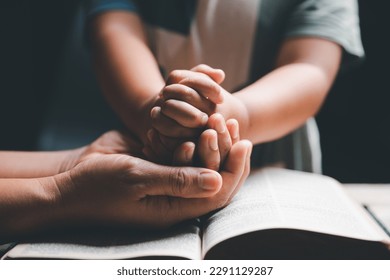 Christian family praying together concept. Child and mother worship God in home. Woman and boy hands praying to god with the bible begging for forgiveness and believe in goodness. - Shutterstock ID 2291129287
